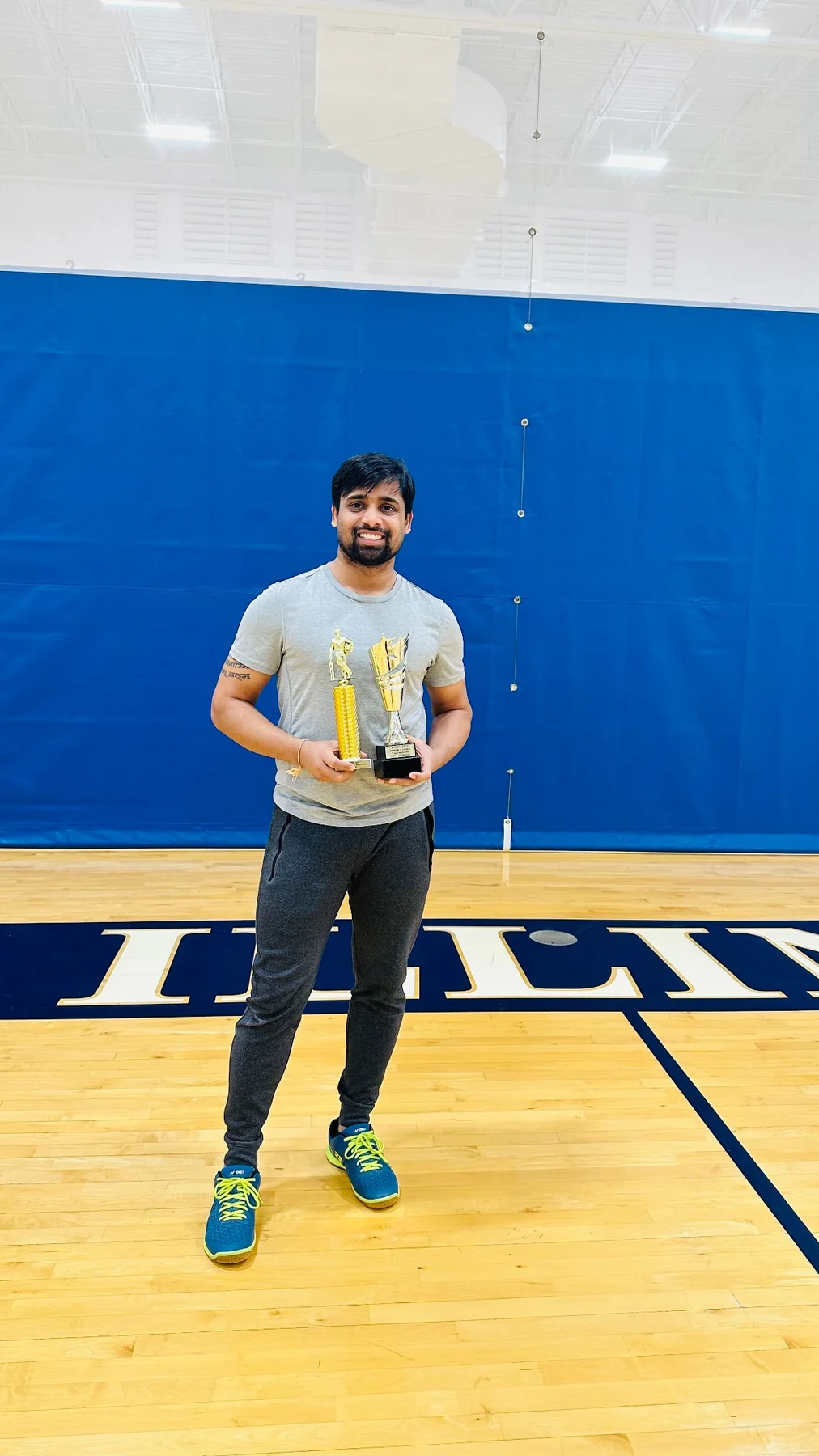 Ravi Teja Alli holding sports trophies